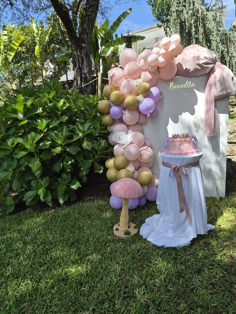 Bolo de aniversário com arco de balões no jardim