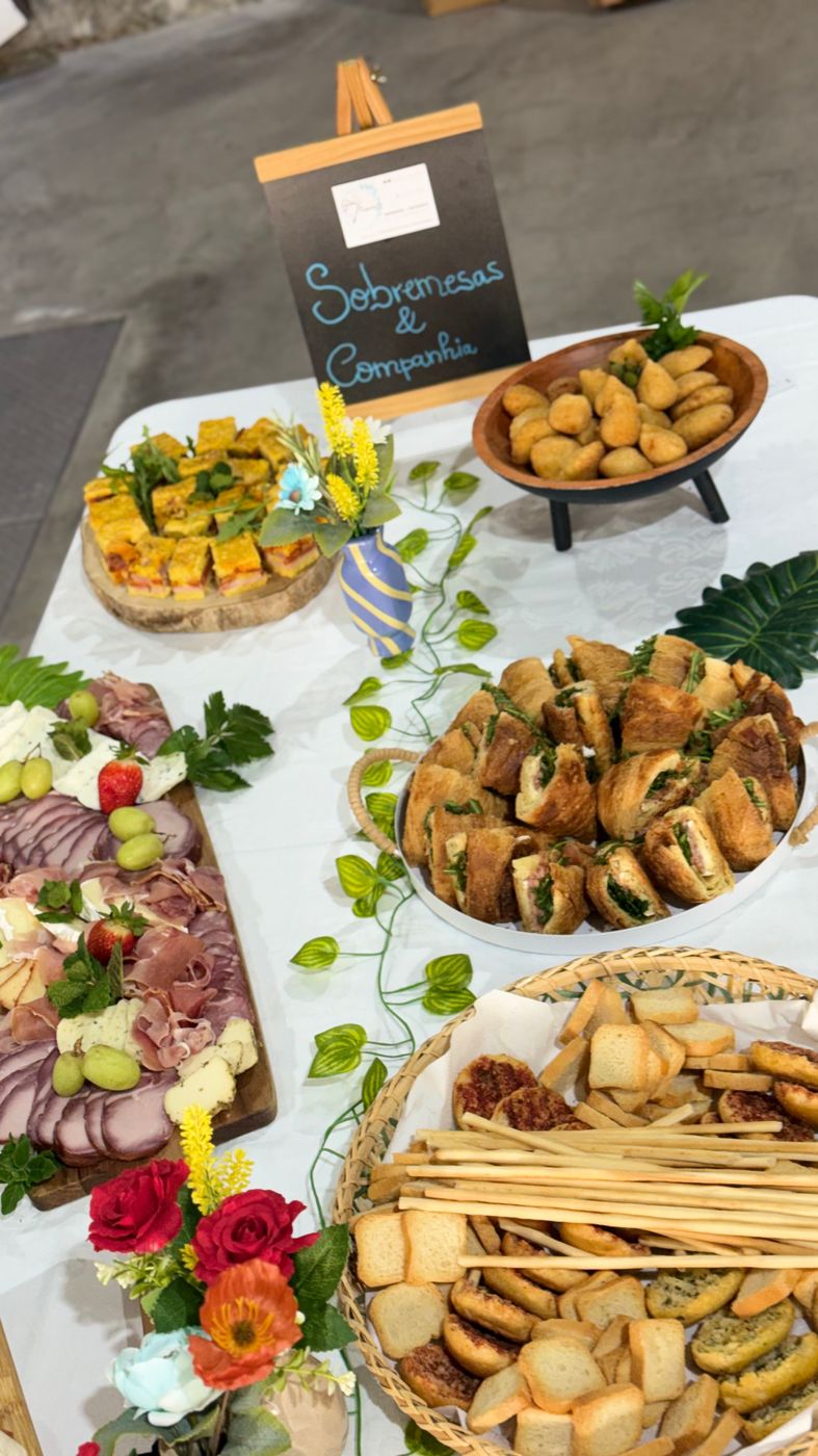 Mesa de salgados e enchidos com o quadro Sobremesas & Companhia
